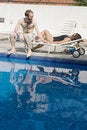 Free Man And Woman Lounging Beside A Pool - Vertical Stock Images - 5770974