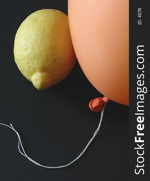 A lemon aside an orange baloon with black background. A lemon aside an orange baloon with black background