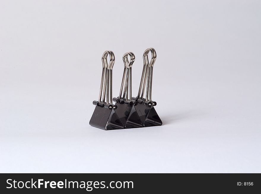 3 medium size binder clips posed in a row on a white background. 3 medium size binder clips posed in a row on a white background