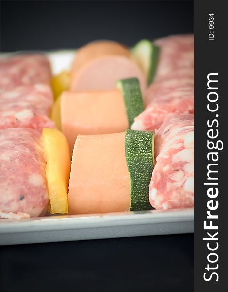 A detail of some little sausages spits on a tray, black background