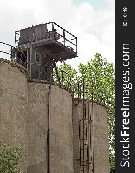 Industrial storage tanks with a platforn on top. A ladder leads to the platform which has a door that allows entry into the tanks. tanks are made of concrete. Industrial storage tanks with a platforn on top. A ladder leads to the platform which has a door that allows entry into the tanks. tanks are made of concrete.