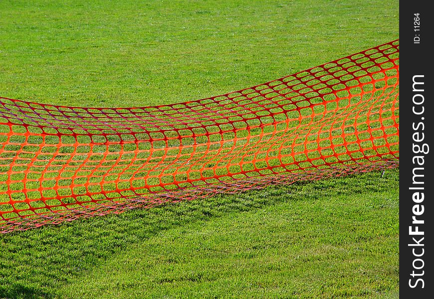 Field of green grass with a red net across
