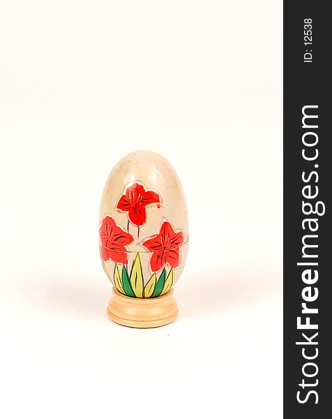 A decorated wooden egg on a stand. egg is cut in half to store knick knacks inside