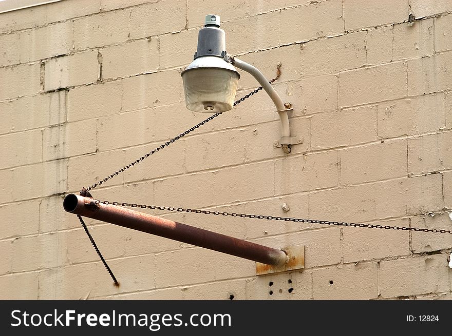 A light hangs over a pipe meant to hold a sign on an abandoned industrial building. A light hangs over a pipe meant to hold a sign on an abandoned industrial building