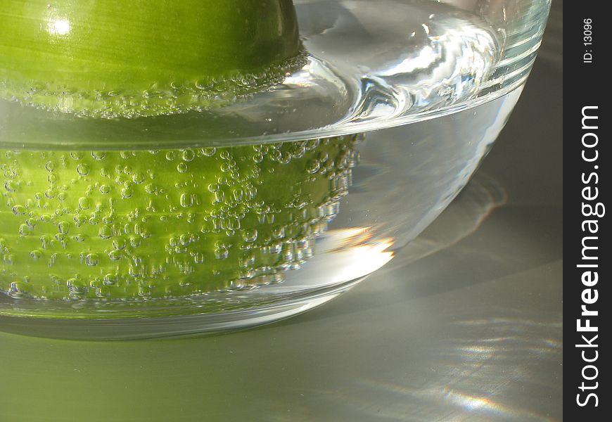 A green apple in a glass of sparkling mineral water. A green apple in a glass of sparkling mineral water.