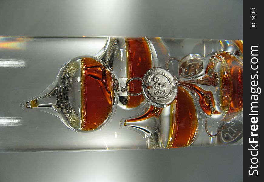 A close-up of an Galileo thermometer. The bubbles are filled with orange liquid. A close-up of an Galileo thermometer. The bubbles are filled with orange liquid.