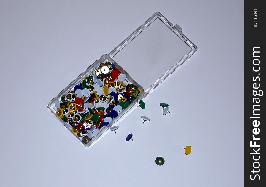 Box of push pins with a few on the floor