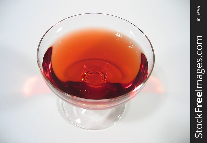 A glass with red liqueur on white background. A glass with red liqueur on white background.