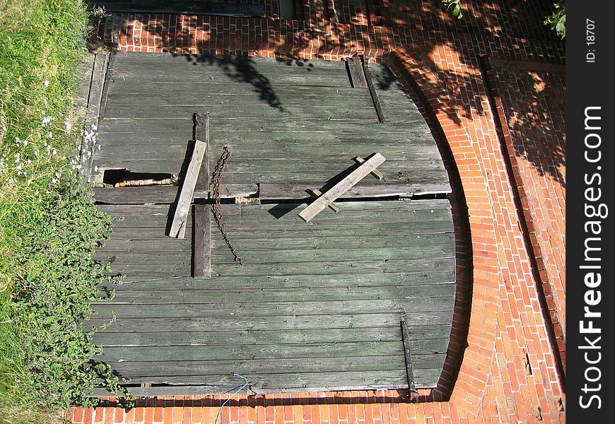 An old broken, weathered barn door in a brick wall.