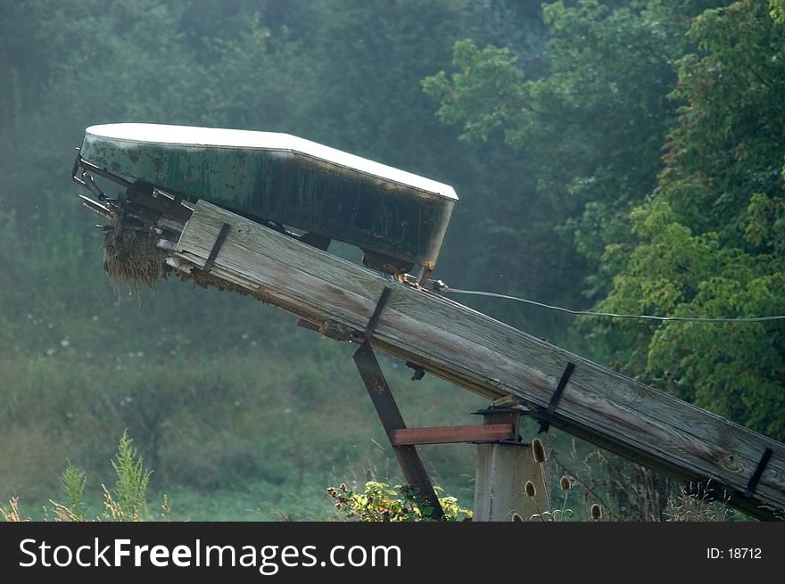 The end of a farm conveyor on wheels sits in a field in North Eastern Ohio. Photographed in the hazy, early morning light