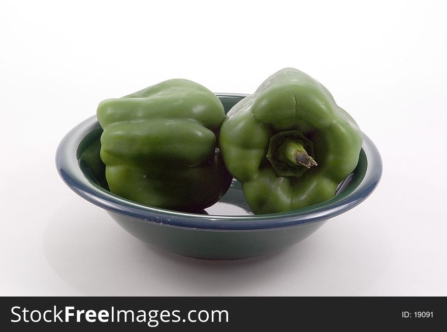 2 large Bell Peppers in a green bowl photographed on a white background. 2 large Bell Peppers in a green bowl photographed on a white background