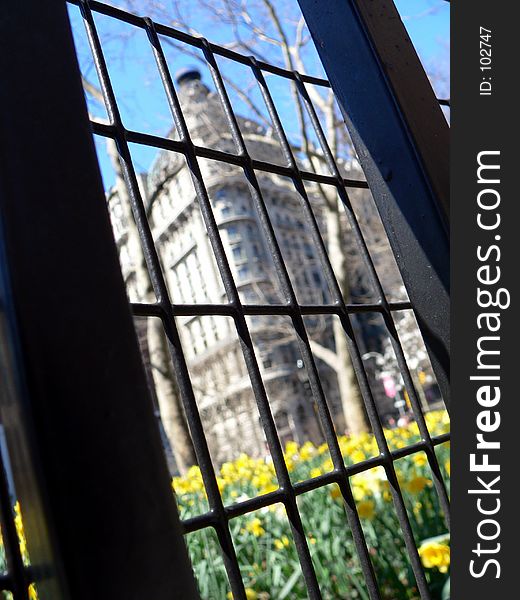 A gate fences in a park and a luxury building. A gate fences in a park and a luxury building