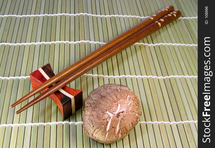 Chopsticks and mushroom over a bamboo background