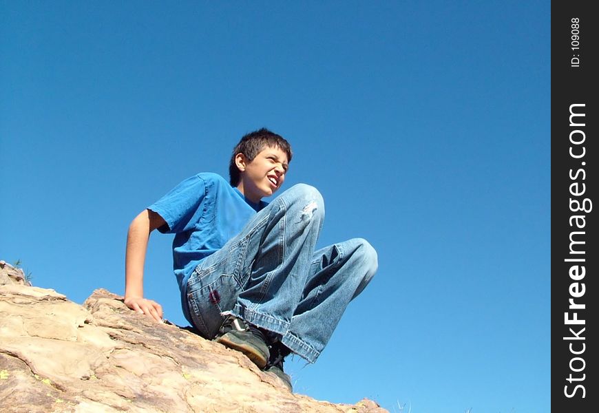 Boy on top of rock at Vasquez Rocks, California against bright blue sky. Boy on top of rock at Vasquez Rocks, California against bright blue sky