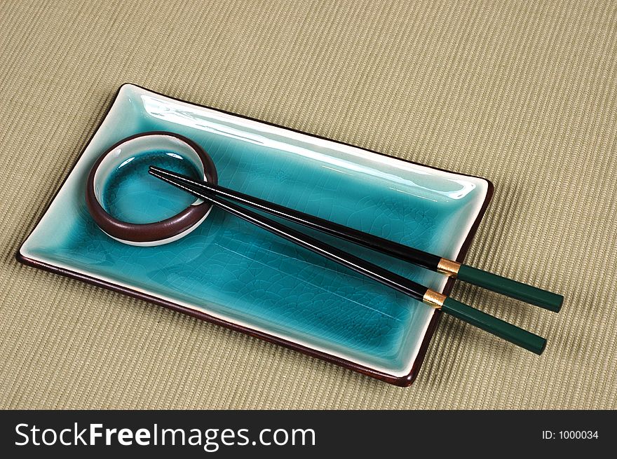 Plate, dipping bowl and chop sticks on green mat