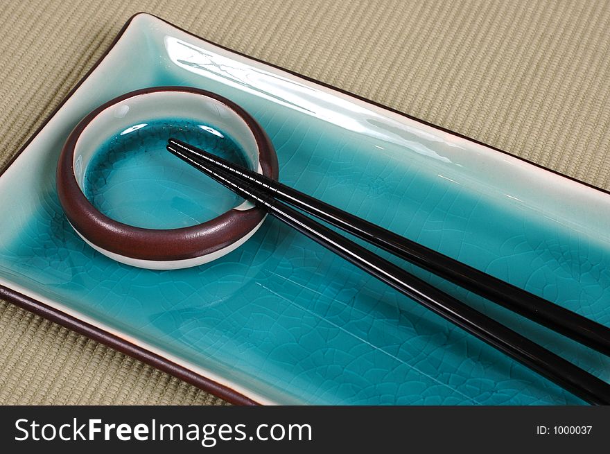 Blue plate, dipping bowl and chop sticks on green mat. Blue plate, dipping bowl and chop sticks on green mat