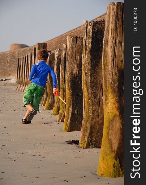 Young boy running in and out of beach posts. Young boy running in and out of beach posts