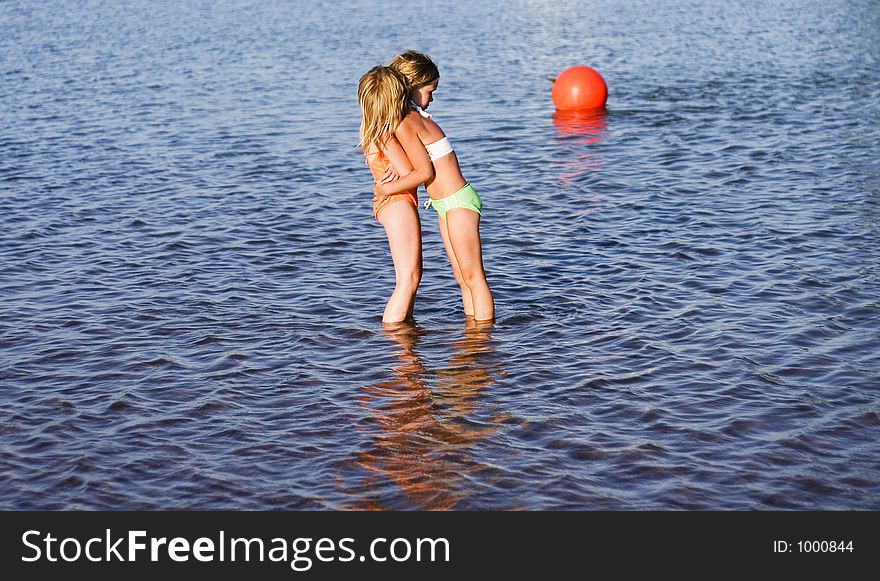 Two girls in the water hugging because they are cold. Two girls in the water hugging because they are cold