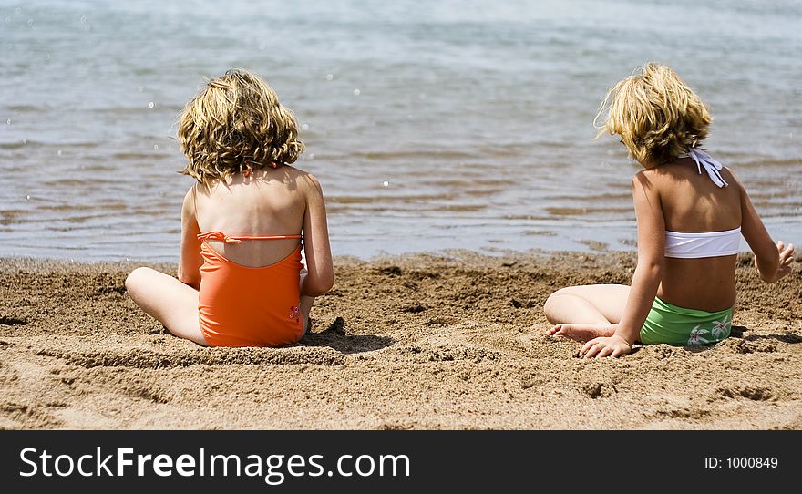 Ryley and peri at the beach sitting in the sand playing in front of the water. Ryley and peri at the beach sitting in the sand playing in front of the water