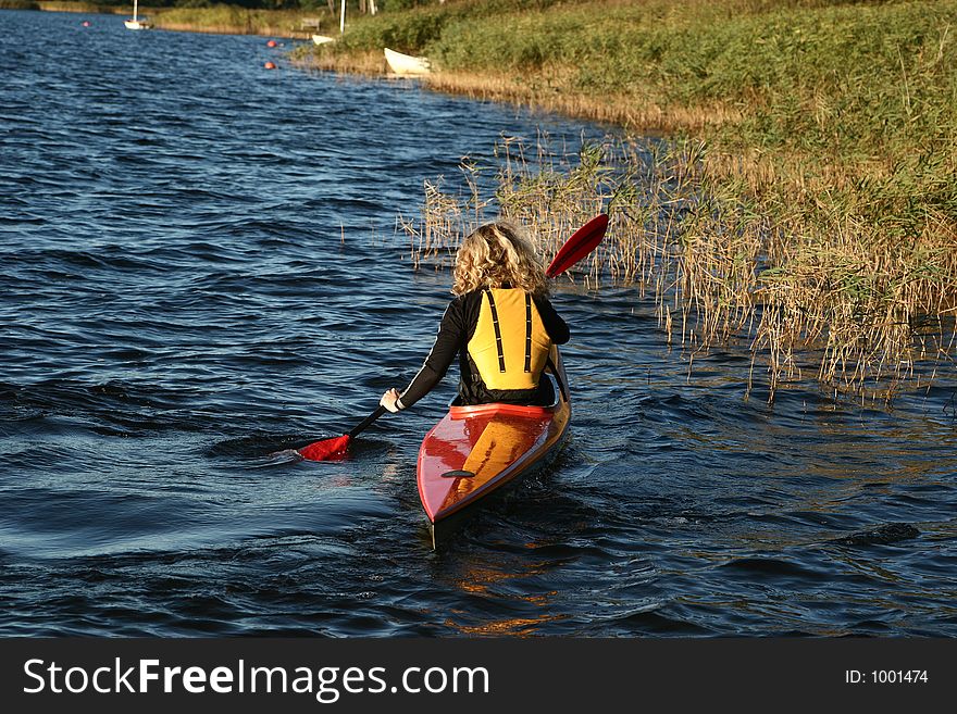 A lake in denmark with a blond girl on a kayack. A lake in denmark with a blond girl on a kayack