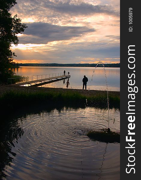 A lake in denmark , a so called bath bridge on a danish lake at the sunset