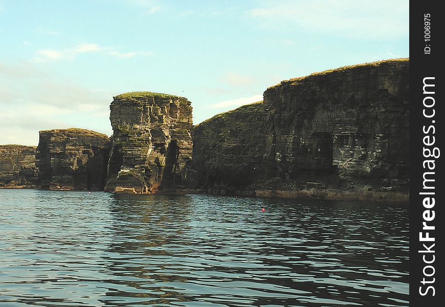 An evening shot from a boat of a cliff stack on the Scottish Coast.