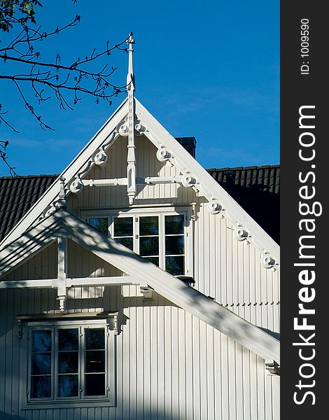 Detail of roof and windows of classic, white, wooden house. Detail of roof and windows of classic, white, wooden house.