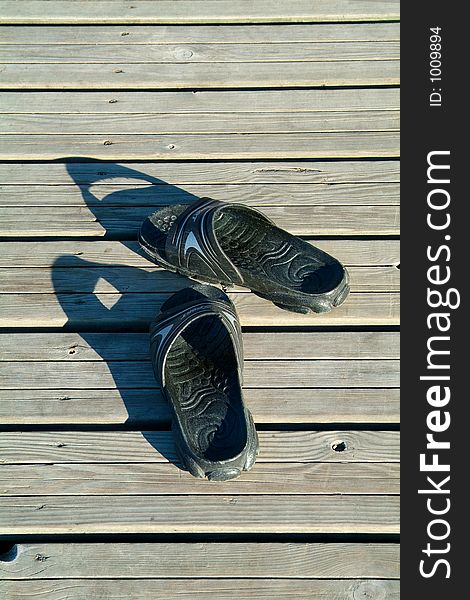 Black plastic sandals left on a wooden pier