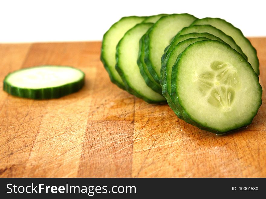 A cucumber in slices on top of kitchen surface. A cucumber in slices on top of kitchen surface