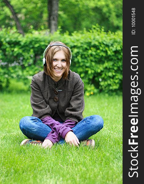 Beautiful girl listening music in ear-phones in park