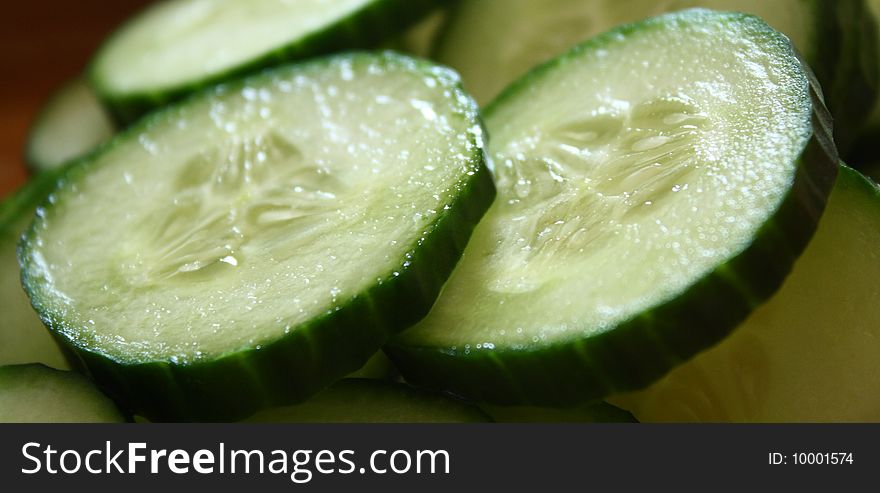 A cucumber in slices on top of kitchen surface. A cucumber in slices on top of kitchen surface