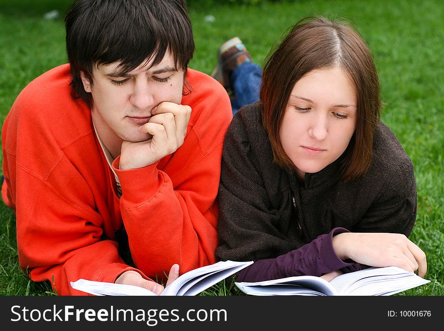 Young students couple reading a books. Young students couple reading a books