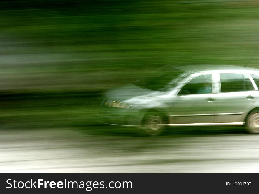 Speedy silver car on road behind trees, Made by Sony Alfa. Speedy silver car on road behind trees, Made by Sony Alfa.