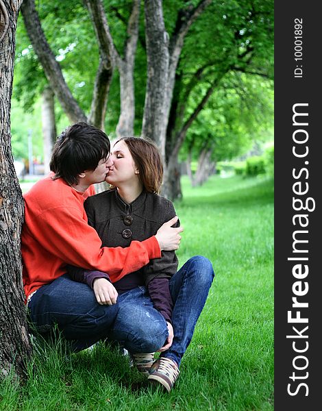 Loving couple kissing under a tree in park