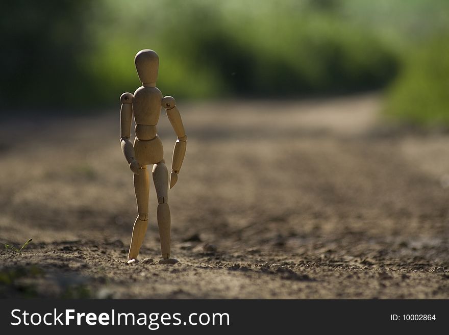 A picture of wooden doll on the road.