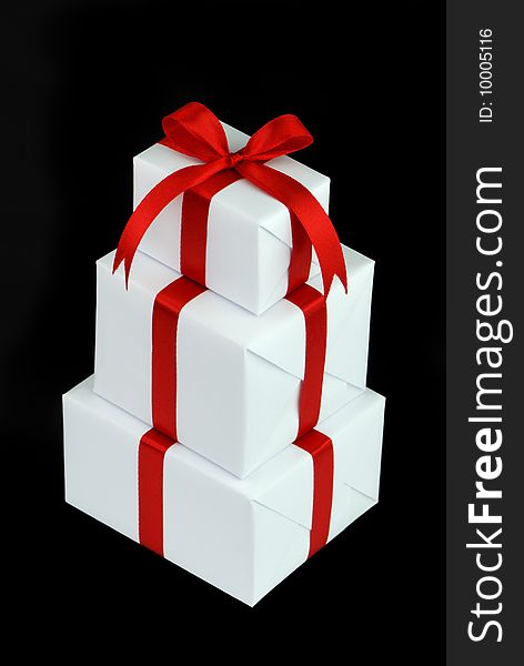 Three white gift boxes with red ribbon isolated on black background