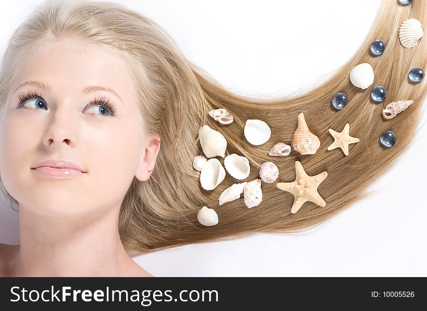 Close-up beautiful blond lying on white background with shell in her hair