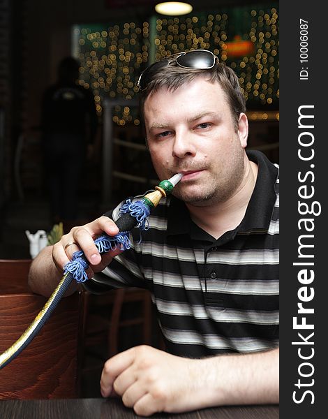 The man poses with a shisha in arabic cafe. The man poses with a shisha in arabic cafe