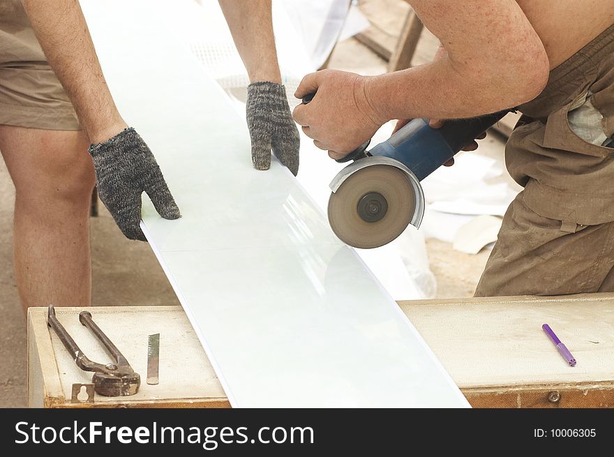 Construction activity: two workers sawing plastic panel