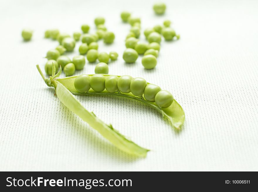 Pod of green peas and small seeds on linen background. Pod of green peas and small seeds on linen background