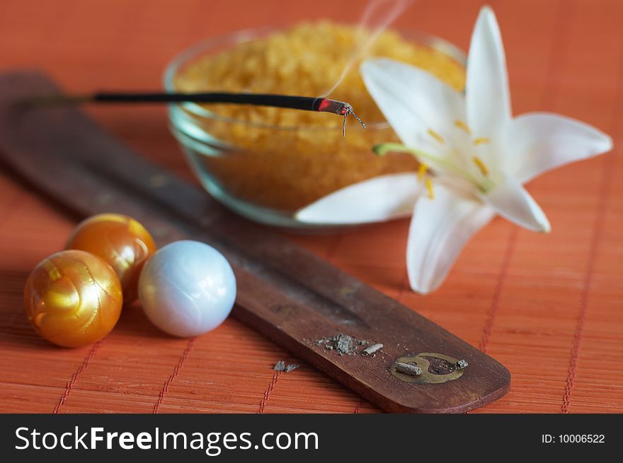 Incense stick, bath salt and white lily on bamboo mat