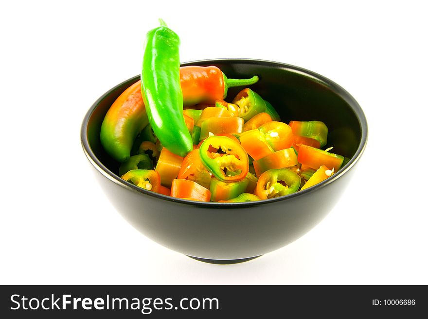 Two chillis and chopped chillis in a black bowl with clipping path on a white background