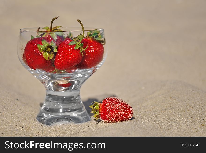 Strawberry in a glass on sand