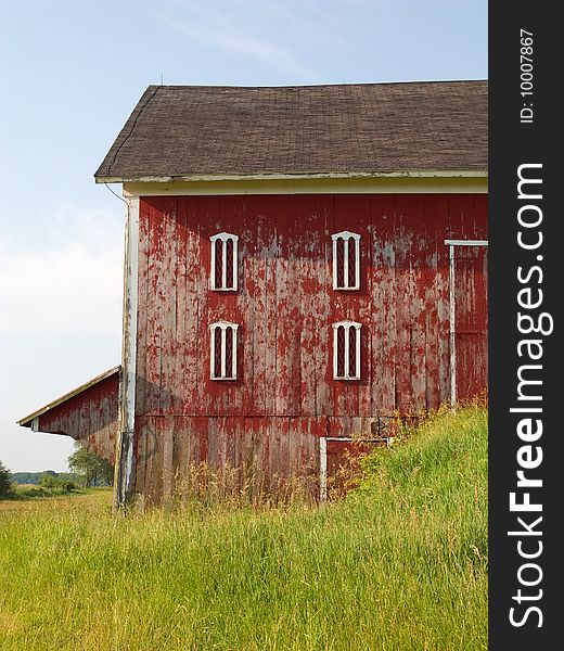 Old red barn with peeling paint surrounded by tall grass sunny Hoosier morning. Old red barn with peeling paint surrounded by tall grass sunny Hoosier morning.