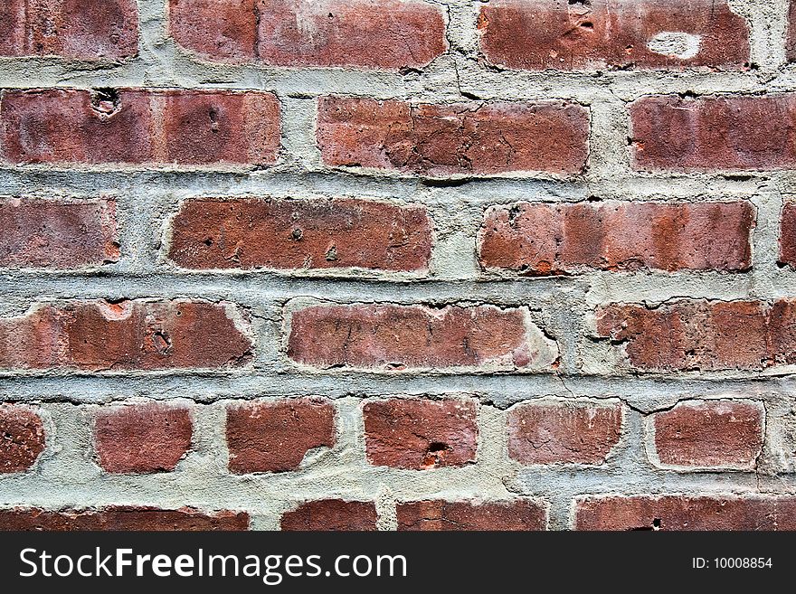 A fragment of a brick wall with cracked cement in between the old bricks. A fragment of a brick wall with cracked cement in between the old bricks.