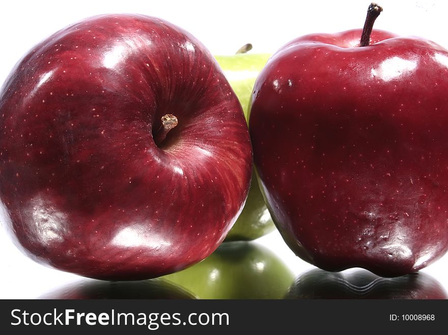 Green and red apples with their reflection