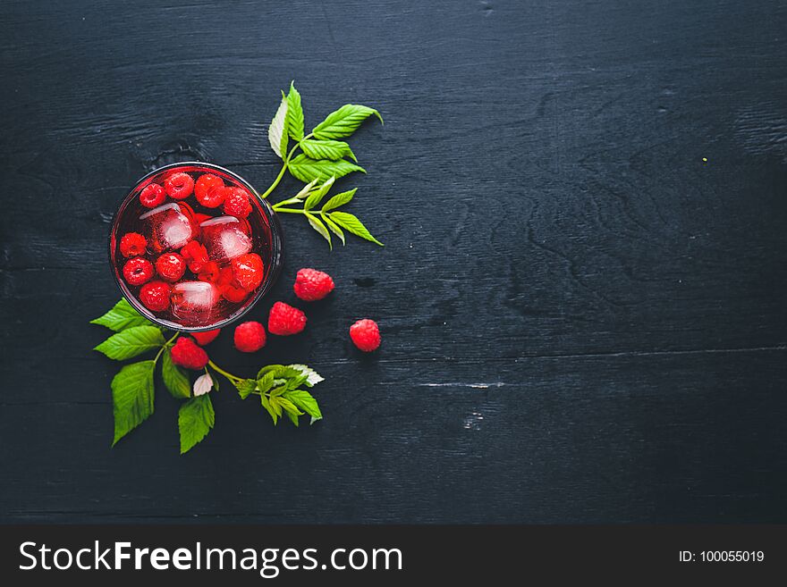 Cocktail of fresh raspberries with ice, on a wooden background. Top view. Free space.