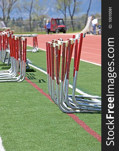 Hurdles alongside the track in the infield in preparation for the hurdles event at a high school track and field meet.