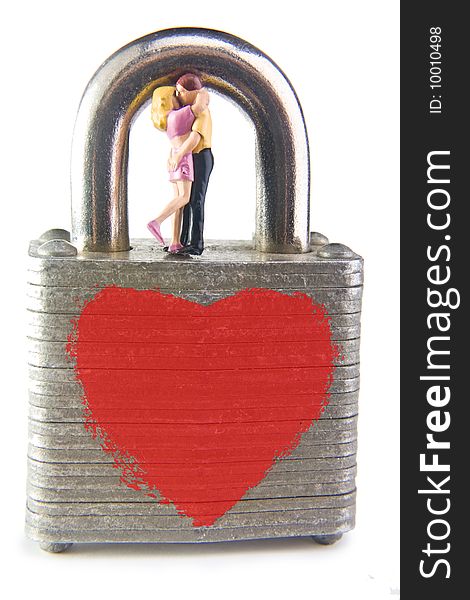 Miniature figures embracing on a padlock with a heart painted on it. Miniature figures embracing on a padlock with a heart painted on it.
