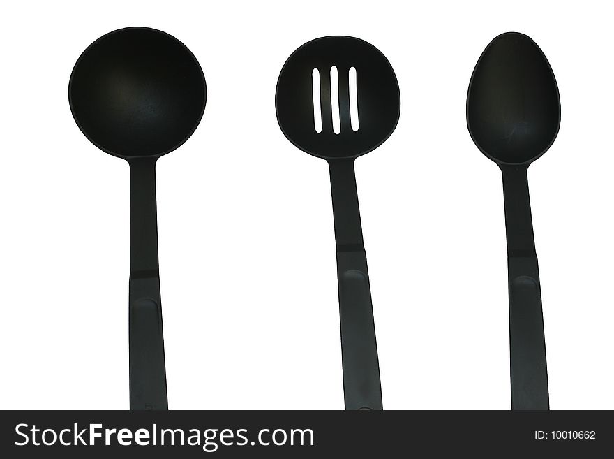 Three sizes of kitchen ladles on an isolated black background